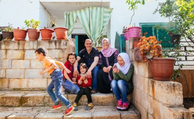 38-year-old Areej - one of Action Against Hunger’s Food Security team leads in Jordan - sits with her family outside their home