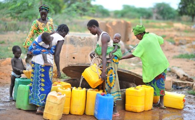 Women and children stand by a well, gathering water.
