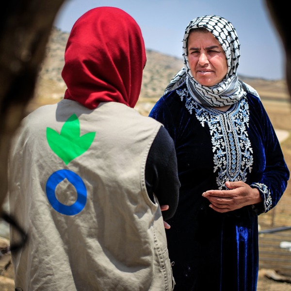 An Action Against Hunger aid worker talks with a Palestinian woman.
