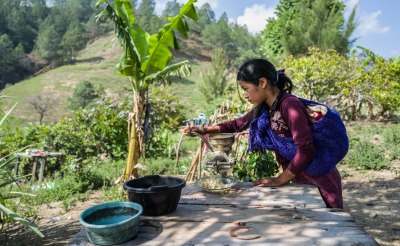 A girl grinds a crop grown in her community.