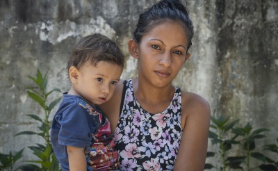 A woman stands, holding a young boy in her arms.