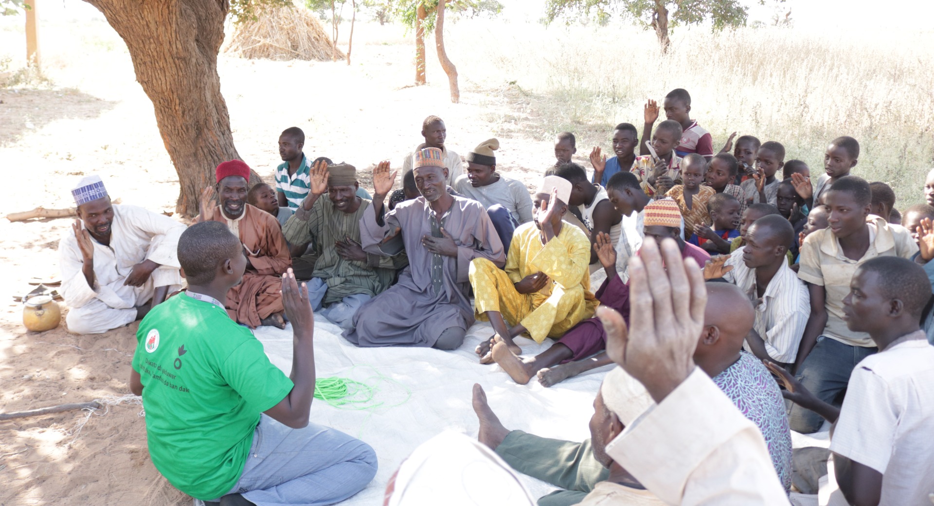 Hassan Mamman and the other men in his fathers’ group raise their hands and recite a pledge, committing to healthy hygiene, safe sanitation, and good nutrition in their community.
