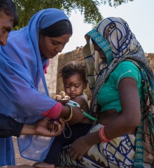 A community health worker shows a mother how to measure her child's nutrition status.