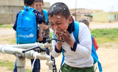 A boy splashes water on his face at a tap installed by Action Against Hunger.