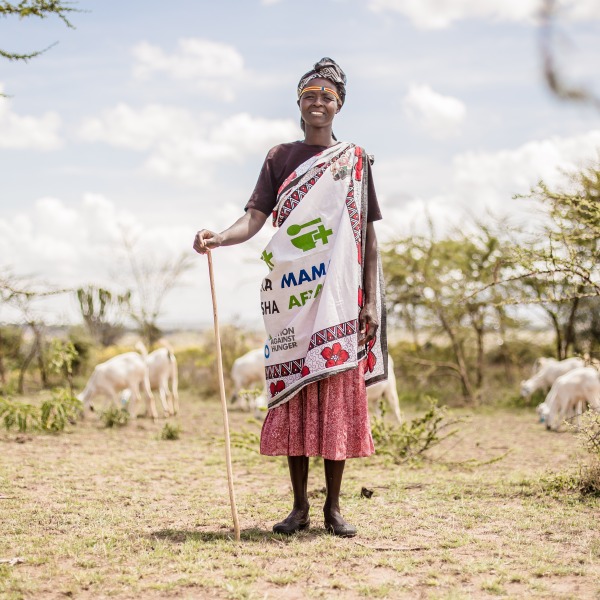 A member of one of Action Against Hunger's mother-to-mother support groups stands in front of her livestock.