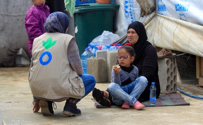 An Action Against Hunger aid worker talks with a refugee family in Lebanon.