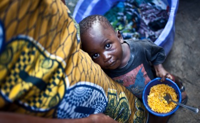A child eats rice standing next to his mother in Monrovia, Liberia.