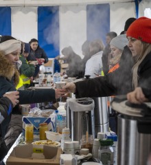 Staff and volunteers distribute hot meals and drinks to Ukrainian refugees.