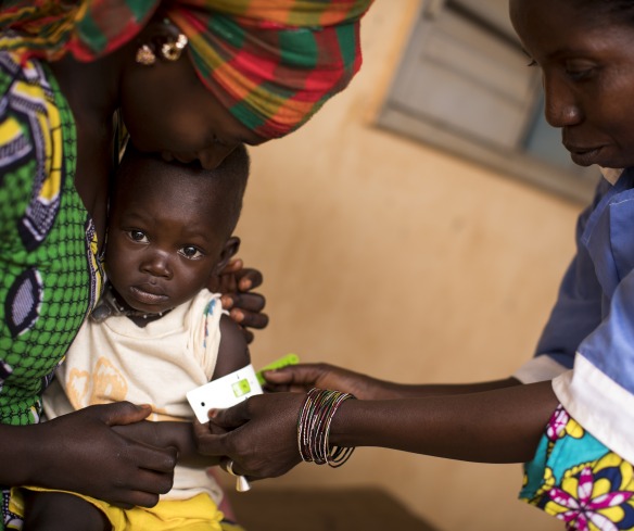 A health worker measures a child for malnutrition.