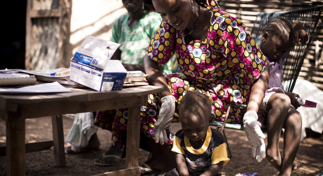 Hawa, an Action Against Hunger-trained community health worker, weighs a child as a part of a routine health check up.