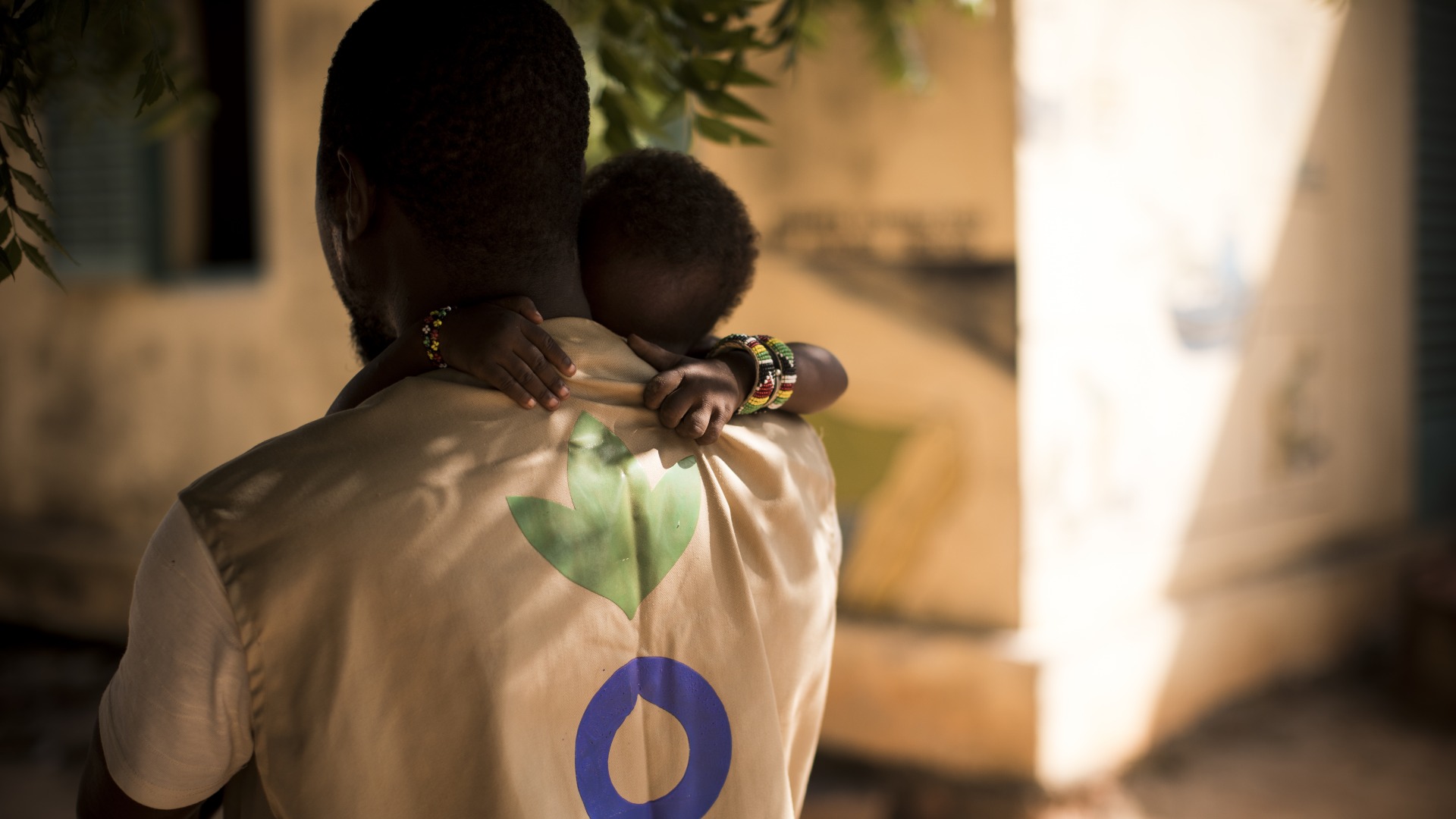 An Action Against Hunger Aid Worker holds a child in his arms in Mali.
