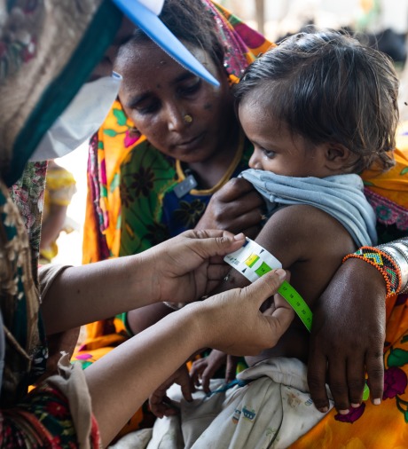 Samina (right), an Action Against Hunger Community Health Worker, checks 4-year-old Kailash's arm with a color-coded measuring tape to see if he has gained weight since her last visit.