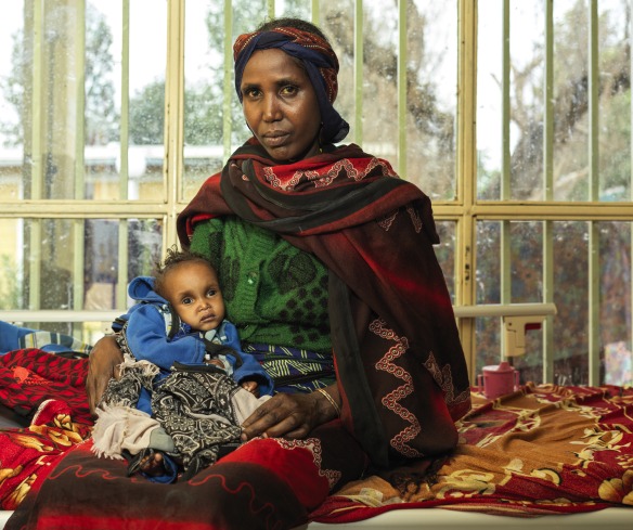 Mother and child sit on a bed at an Action Against Hunger nutrition center in Ethiopia.
