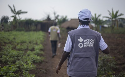An Action Against Hunger aid worker walks through a field.